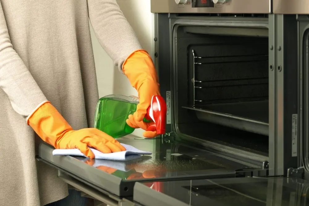 Nettoyage de l&rsquo;int&eacute;rieur d&rsquo;un four avec produit m&eacute;nager lors d&rsquo;un entretien r&eacute;gulier de la cuisine.