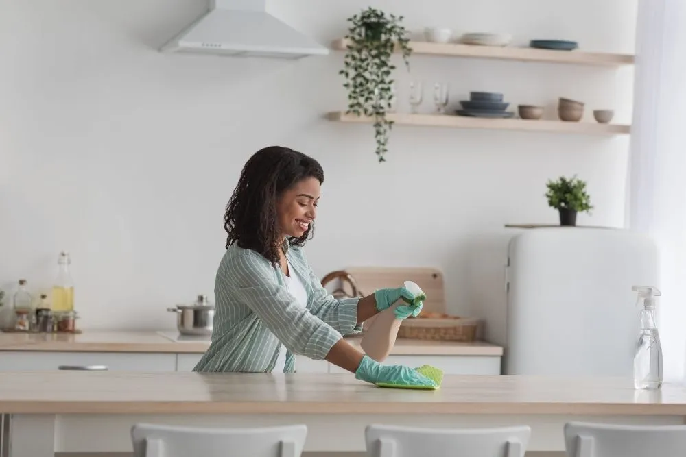 Nettoyage du plan de travail en cuisine avec produit m&eacute;nager dans le cadre d&rsquo;un entretien r&eacute;gulier du logement.